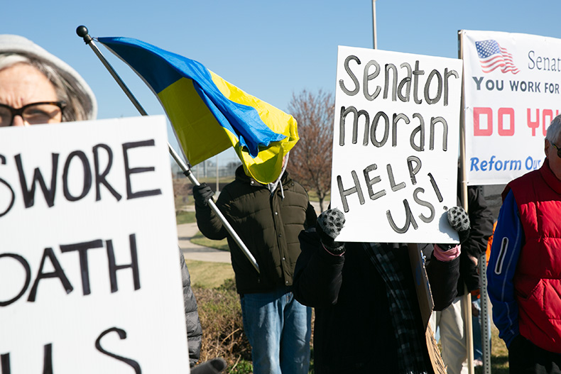 Protestors call on U.S. Sen. Jerry Moran to push back against President Donald Trump, and fly a Ukrainian flag. Photo credit Juliana Garcia.